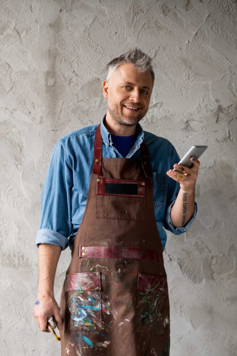 Happy and successful painter with smartphone and paintbrush.jpg