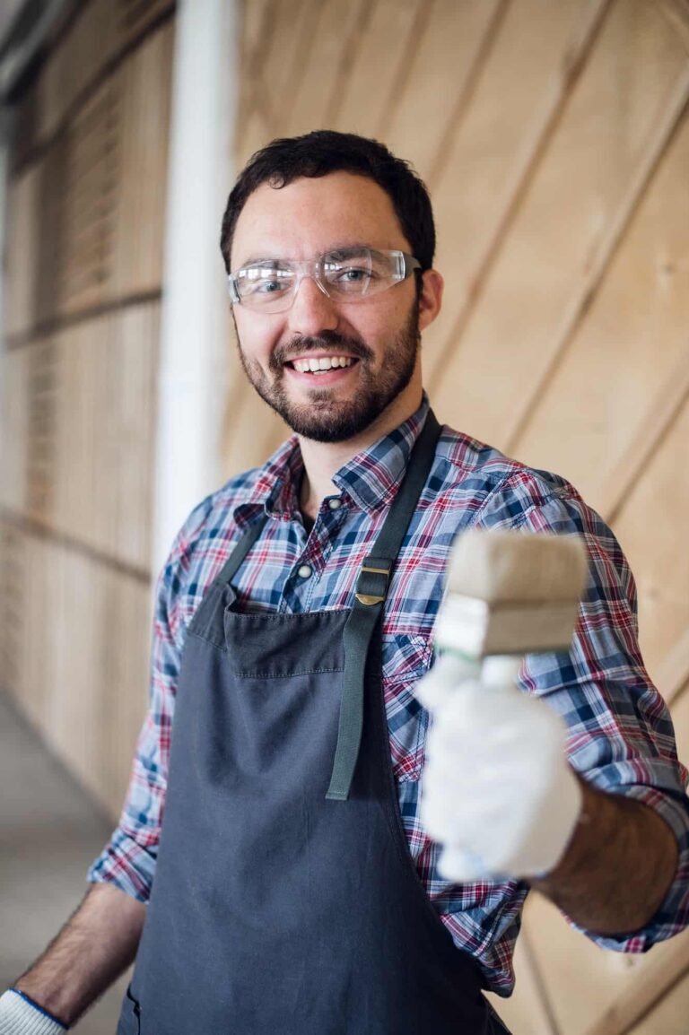 Happy young painter holding paint brush and showing it to camera.jpg